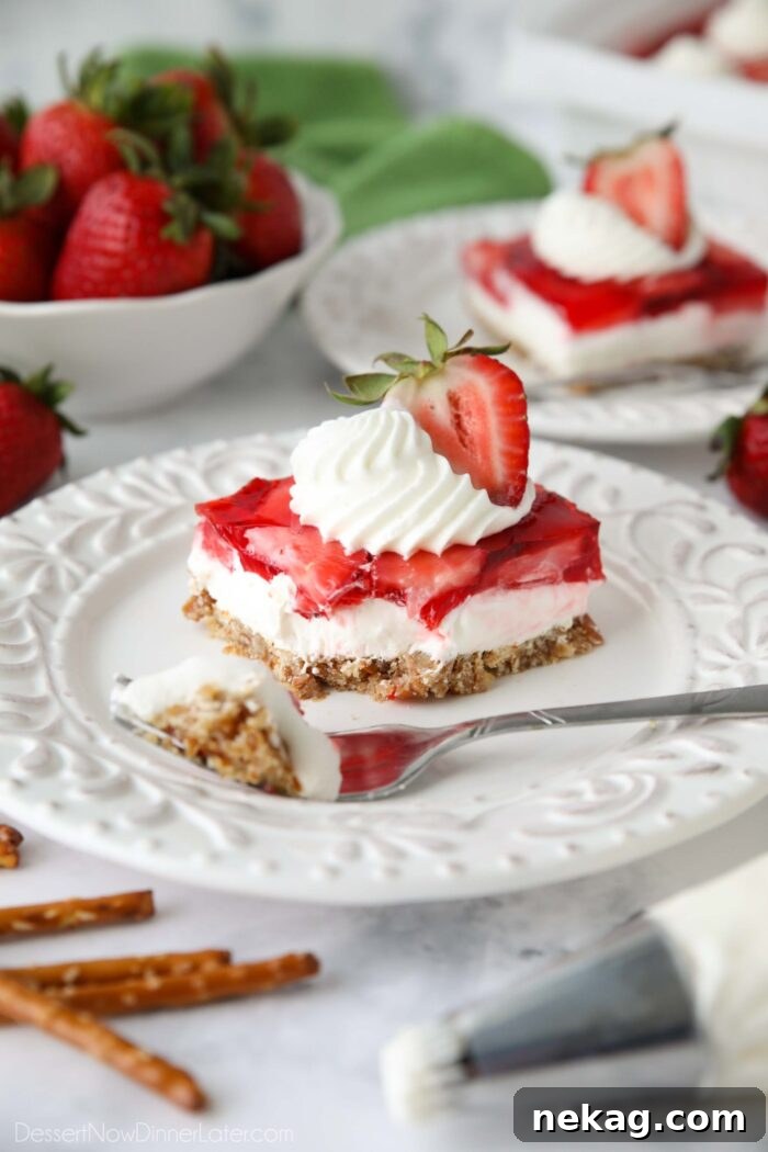Fork full removed of a piece of strawberry pretzel salad dessert.