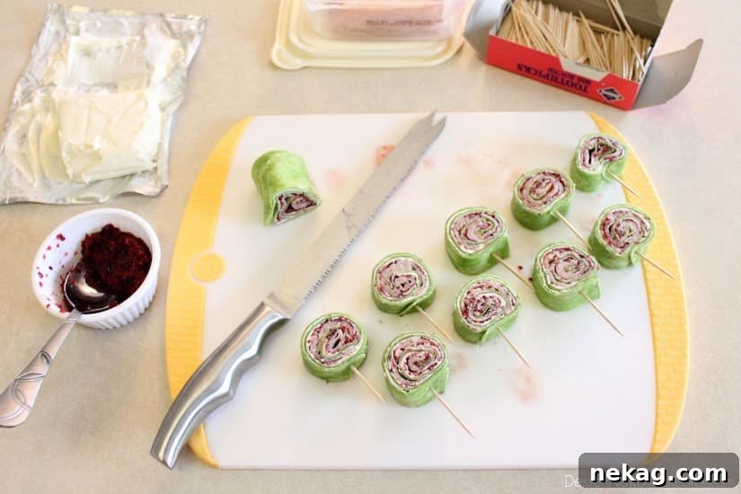 Cranberry Turkey Pinwheels have layers of cream cheese, spicy-sweet cranberry salsa, and thinly sliced turkey all rolled up in a spinach tortilla for a delicious party appetizer! From DessertNowDinnerLater.com