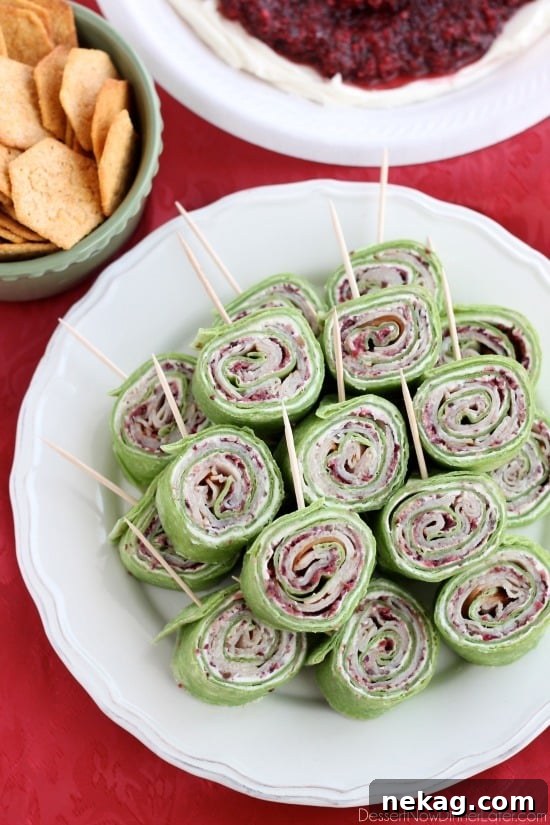 Cranberry Turkey Pinwheels have layers of cream cheese, spicy-sweet cranberry salsa, and thinly sliced turkey all rolled up in a spinach tortilla for a delicious party appetizer! From DessertNowDinnerLater.com