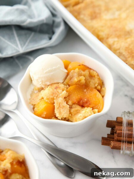 Peach dump cake (aka peach cobbler with cake mix) in a bowl with a scoop of vanilla ice cream.