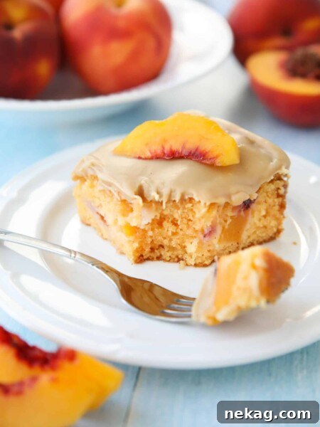 Fork full of peach cake with brown sugar frosting taken out of a slice on a plate.