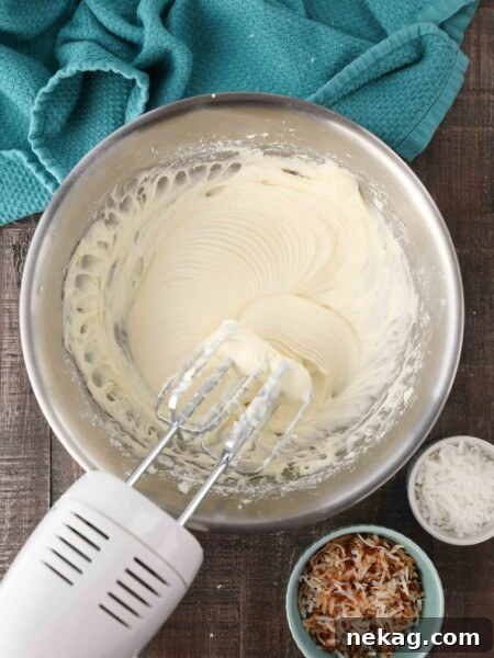 Mixing bowl and beaters filled with coconut cream cheese frosting.