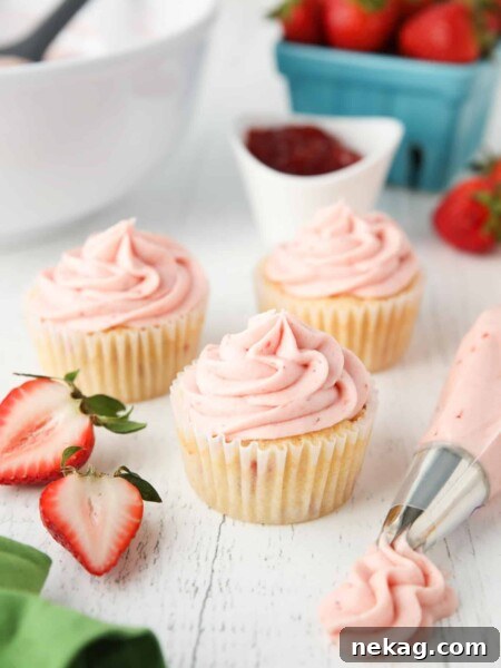 Strawberry frosting piped onto cupcakes.