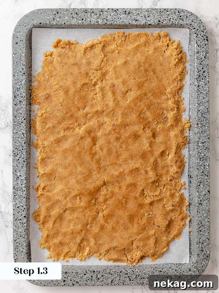 Spreading it thin on parchment helps the crumb cake topping firm up quickly before baking.