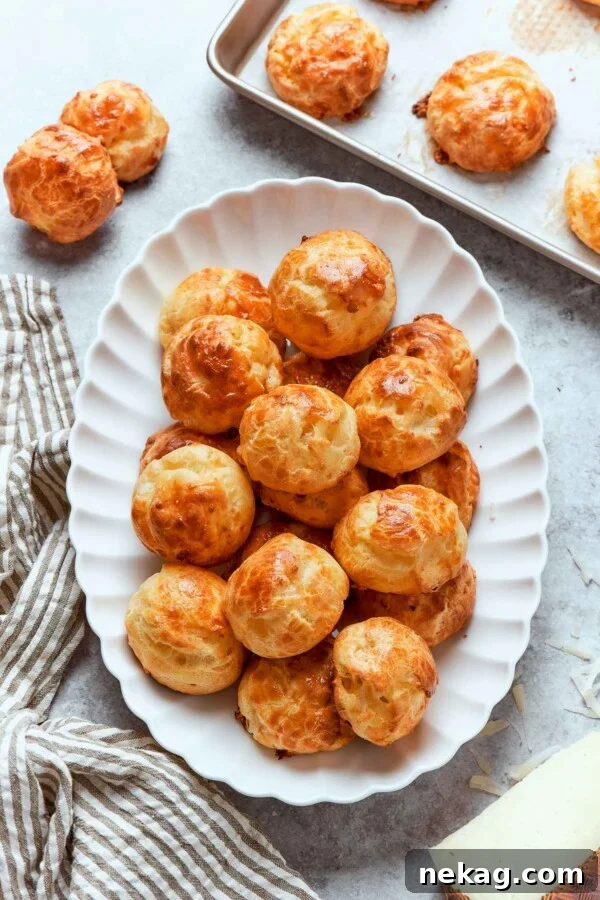Gougères arranged on white plate highlighting golden color and uniform puffed shape.