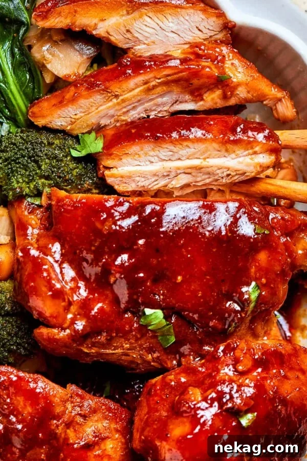 Thick gochujang sauce coating pan-seared chicken pieces with mushrooms in a bowl.