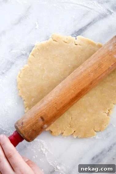 Old Fashioned Almond Pie Crust on marble surface with antique rolling pin.