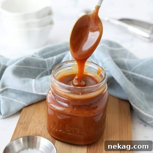 Homemade Salted Caramel Sauce Recipe 10 Homemade salted caramel sauce in a jar being drizzled with a spoon.