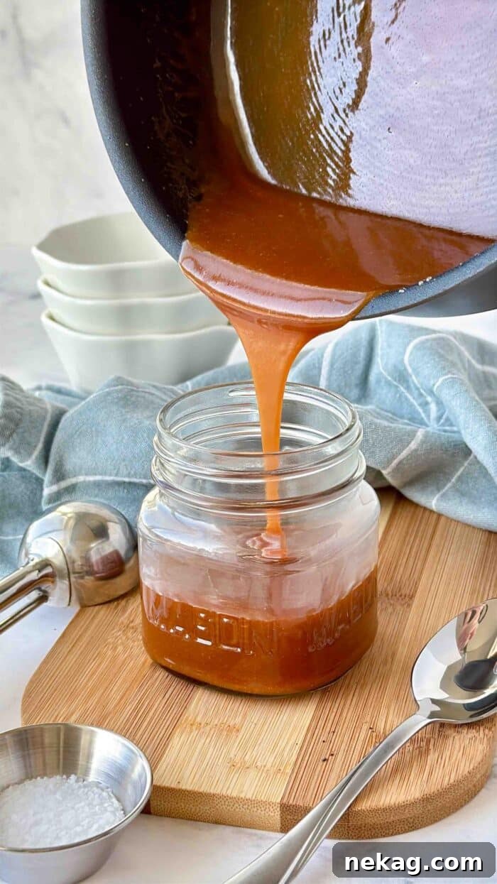 Homemade Salted Caramel Sauce Recipe 7 Pouring salted caramel sauce into a mason jar.