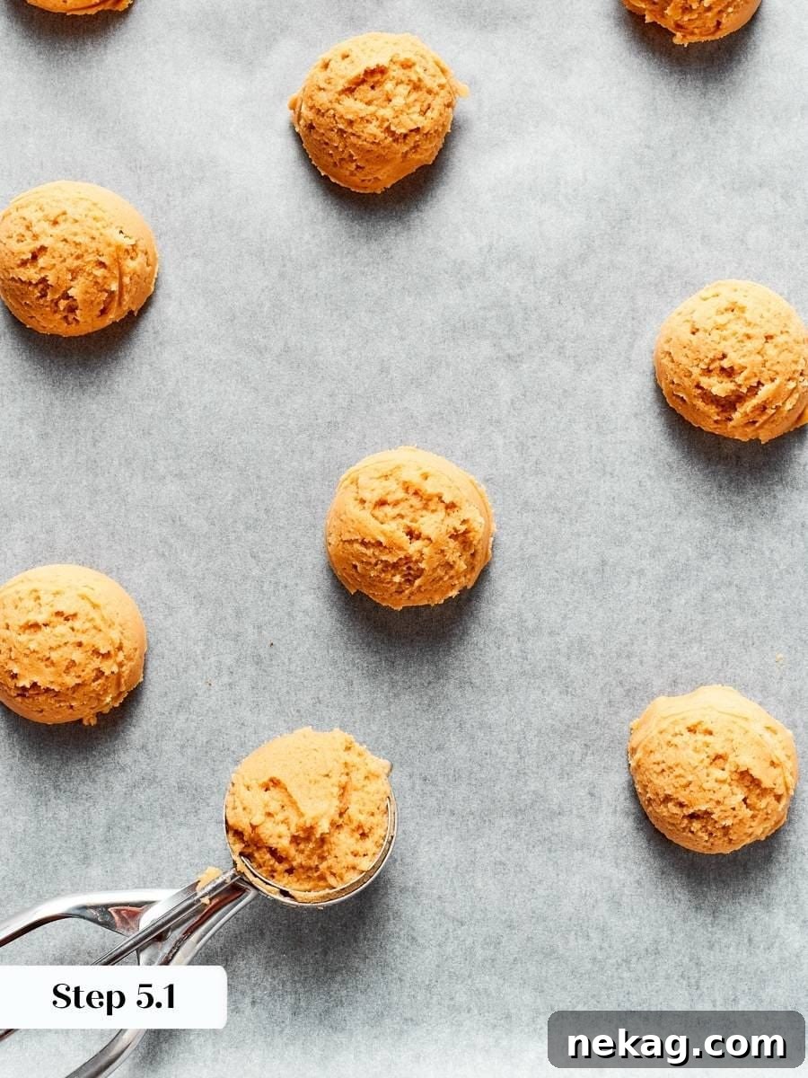 Squeezing each portion firmly compacts the crumbly dough that chewy peanut butter cookies rely on.