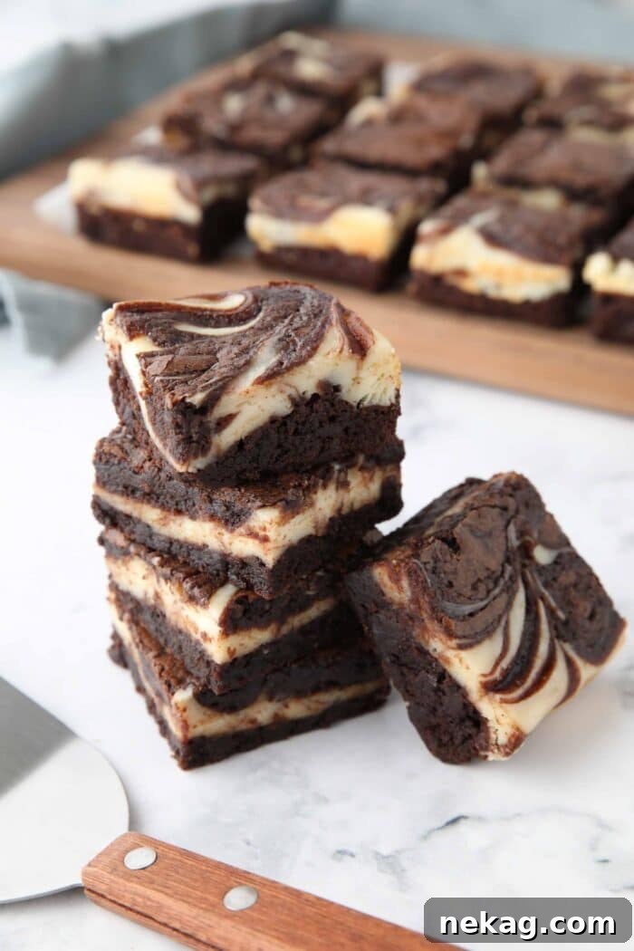 Fudgy Cheesecake Brownies Recipe 3 Stack of cream cheese brownies with swirls of brownie and cheesecake.